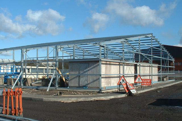 The steel framework of a building under construction in front of a blue sky