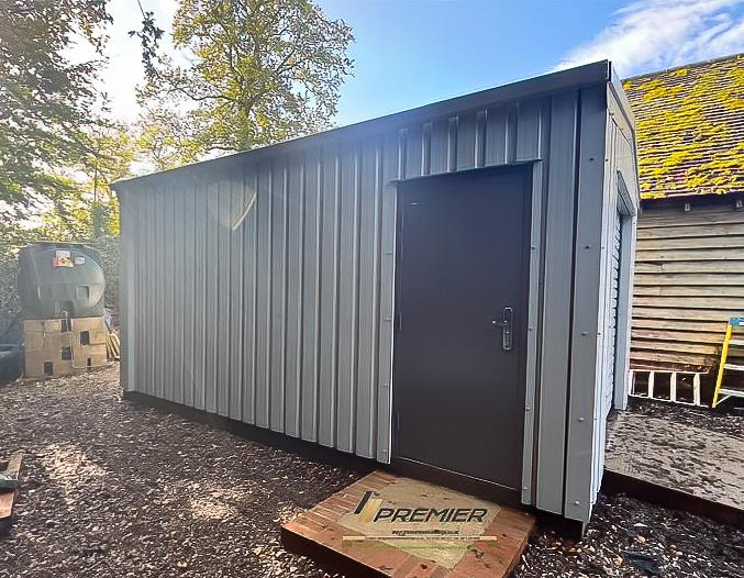 Side profile of a light grey steel building highlighting the personnel door and the vertical ribbed paneling.